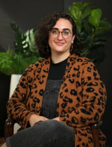 Layla Tahmassebi is a Middle Eastern femme non-binary person with curly brown hair and glasses