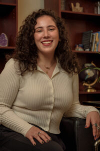 Stef Stone is a white Jewish woman with curly brown hair.
